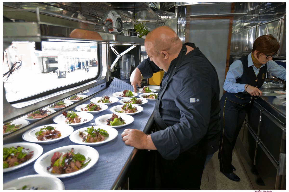 Professional chefs preparing gourmet salad dishes in El Transcantabrico Gran Lujo train kitchen