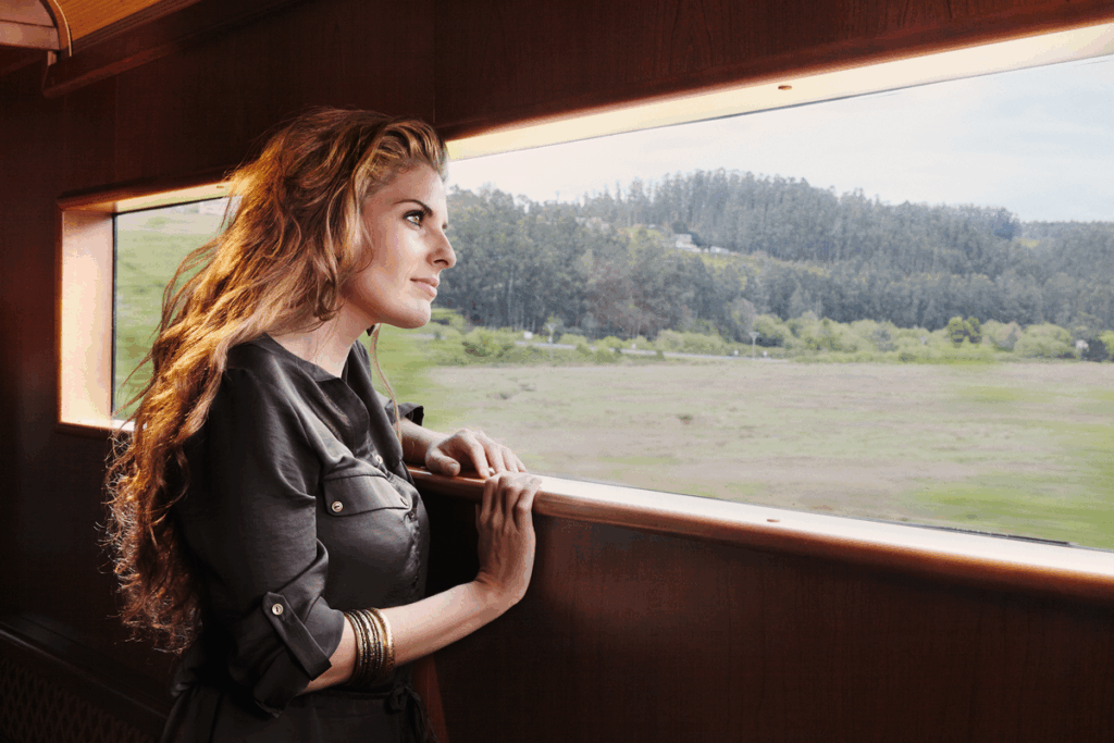 Woman enjoying scenic mountain views from El Transcantábrico Gran Lujo luxury train window