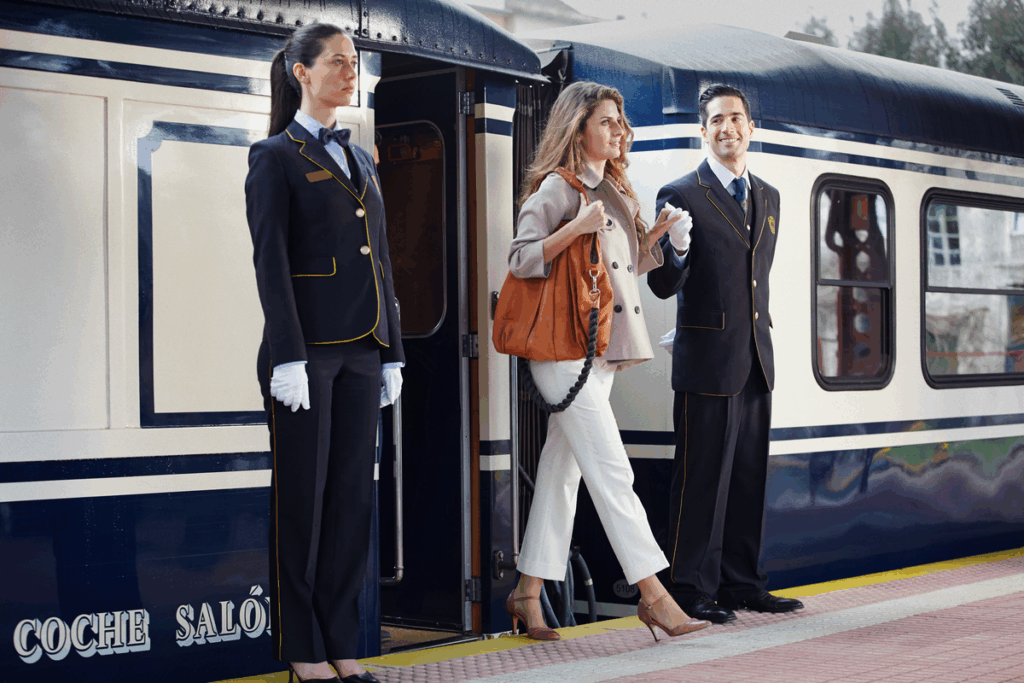 Elegant passenger disembarking El Transcantabrico luxury train with uniformed staff assistance